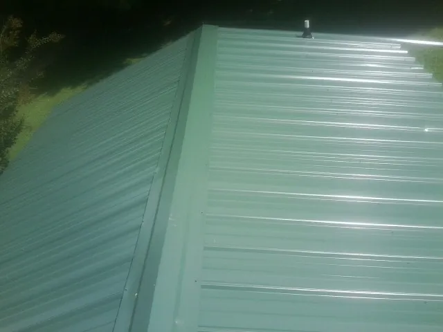 New green metal panels meeting at the ridge of a roof in Hubbard