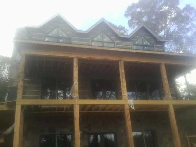 Dormers and porch framing on a large log home under construction — Roof Coating work by our crew in Hubbard