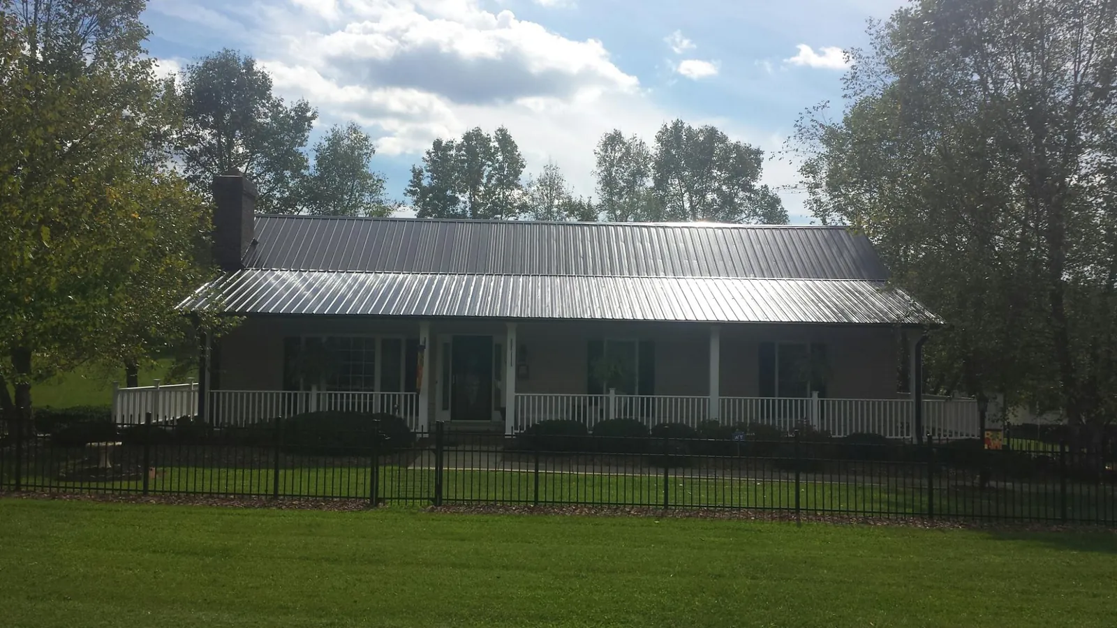 Gray metal roof on a brick ranch with a full width front porch — Gutter Guard Installation work by our crew in Hubbard